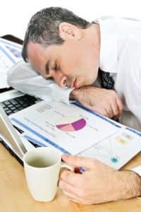 Tired businessman fell asleep at his desk while looking for sleep references