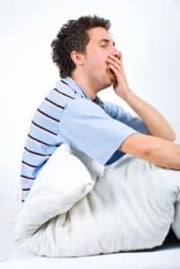 Young man on bed yawning - the sleep therapy treatment works!